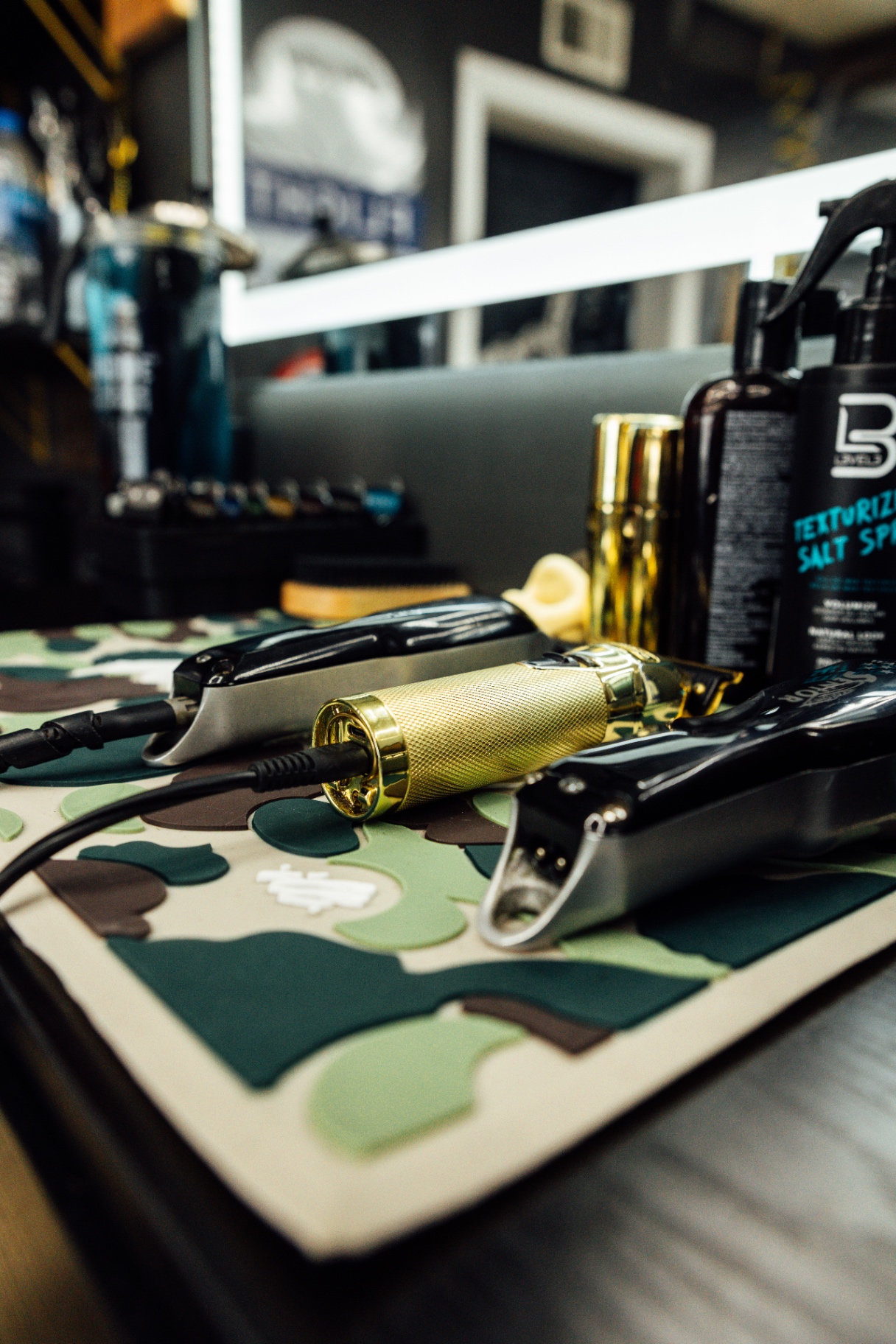 Gold and black professional clippers on a camo mat